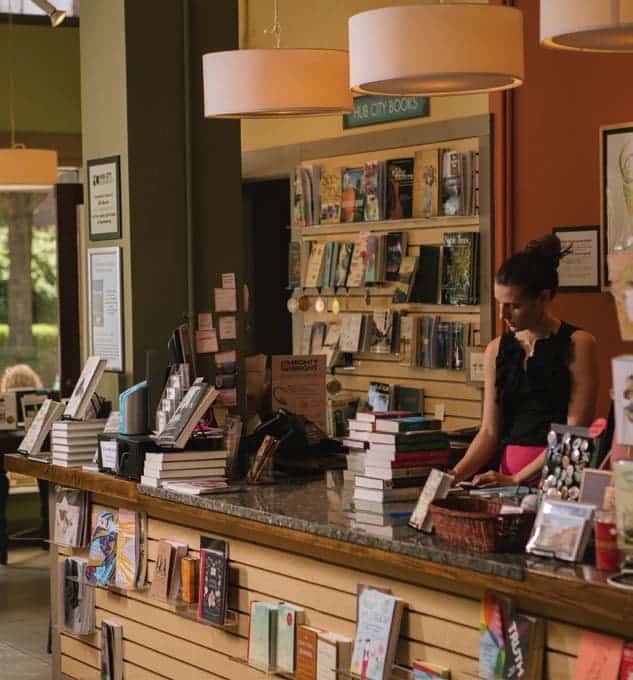 front counter and lady with stack of books at hub city bookshop in spartanburg, sc