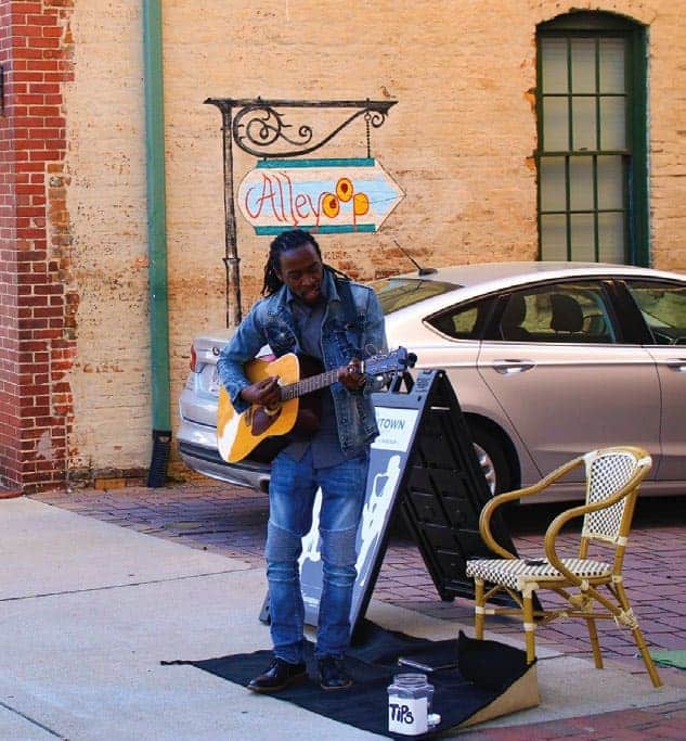 man playing guitar on sidewalk in spartanburg, sc